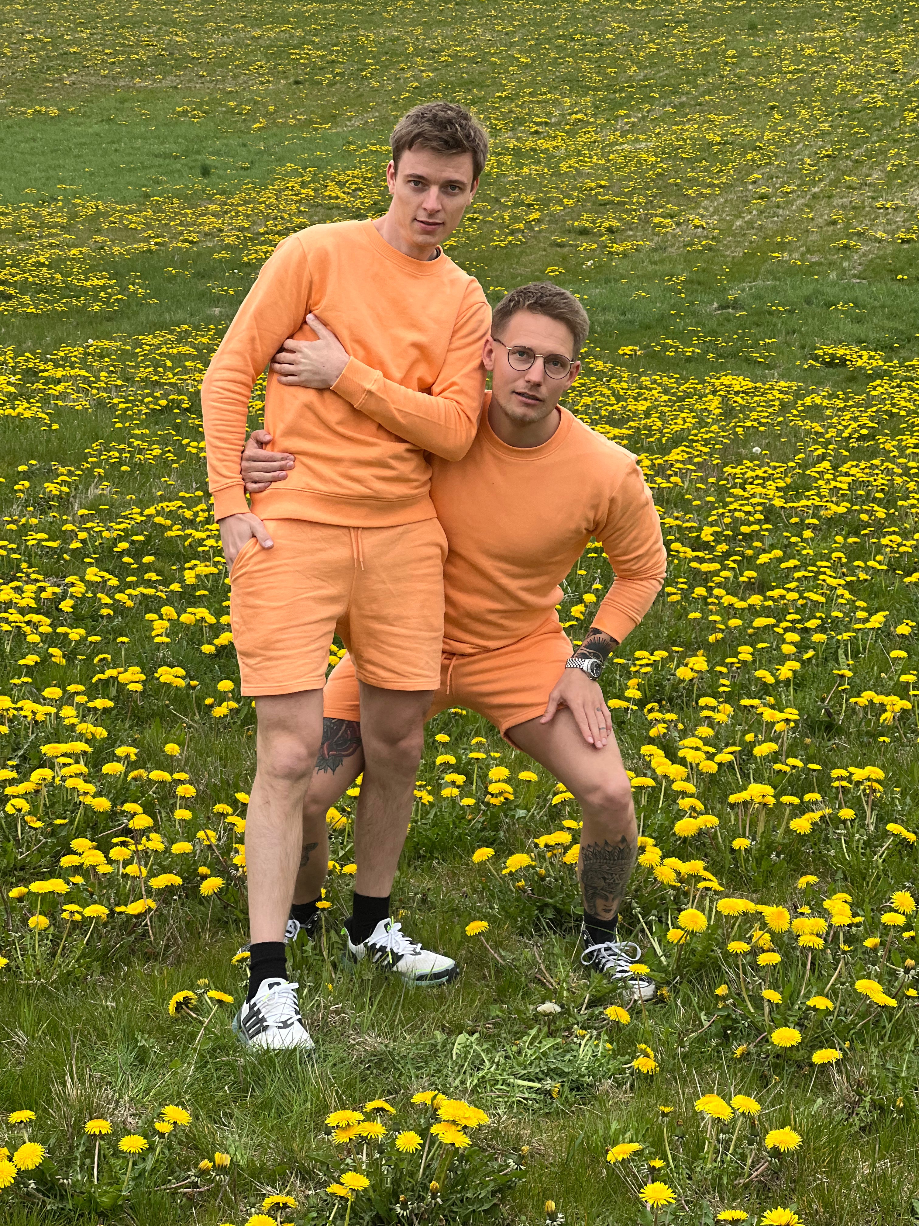 To mænd holder om hinanden, mens de er iført et sommersæt i en ferskenfarve.